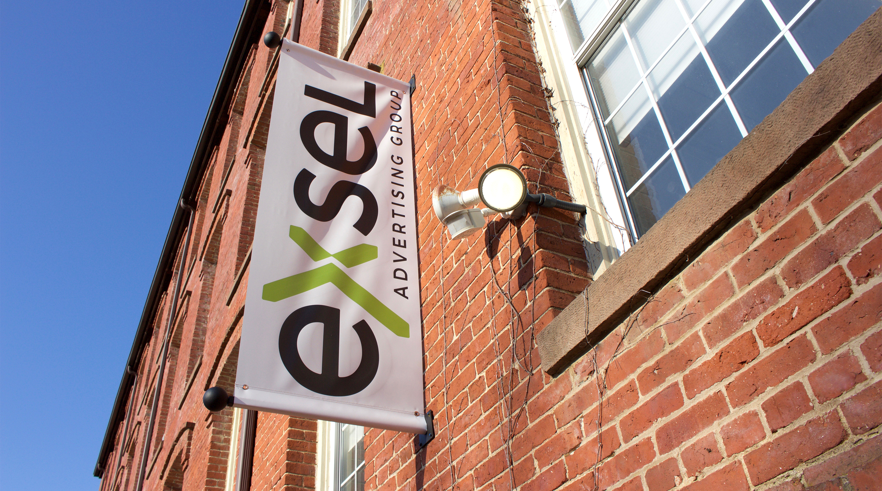 Rebrand of Exsel Advertising Group. New sign on side of brick building.